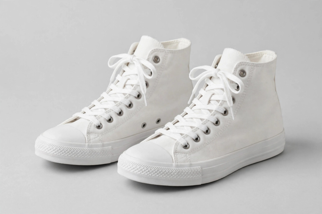 Pair of white canvas high-top sneakers with rubber toe caps on a light background